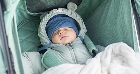 Bebis i overall sover i vagn