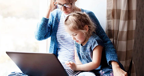 Mamma med barn kollar på laptop